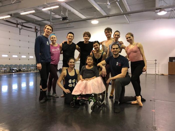 Kate and dance company with young girl in wheelchair in pink tutu